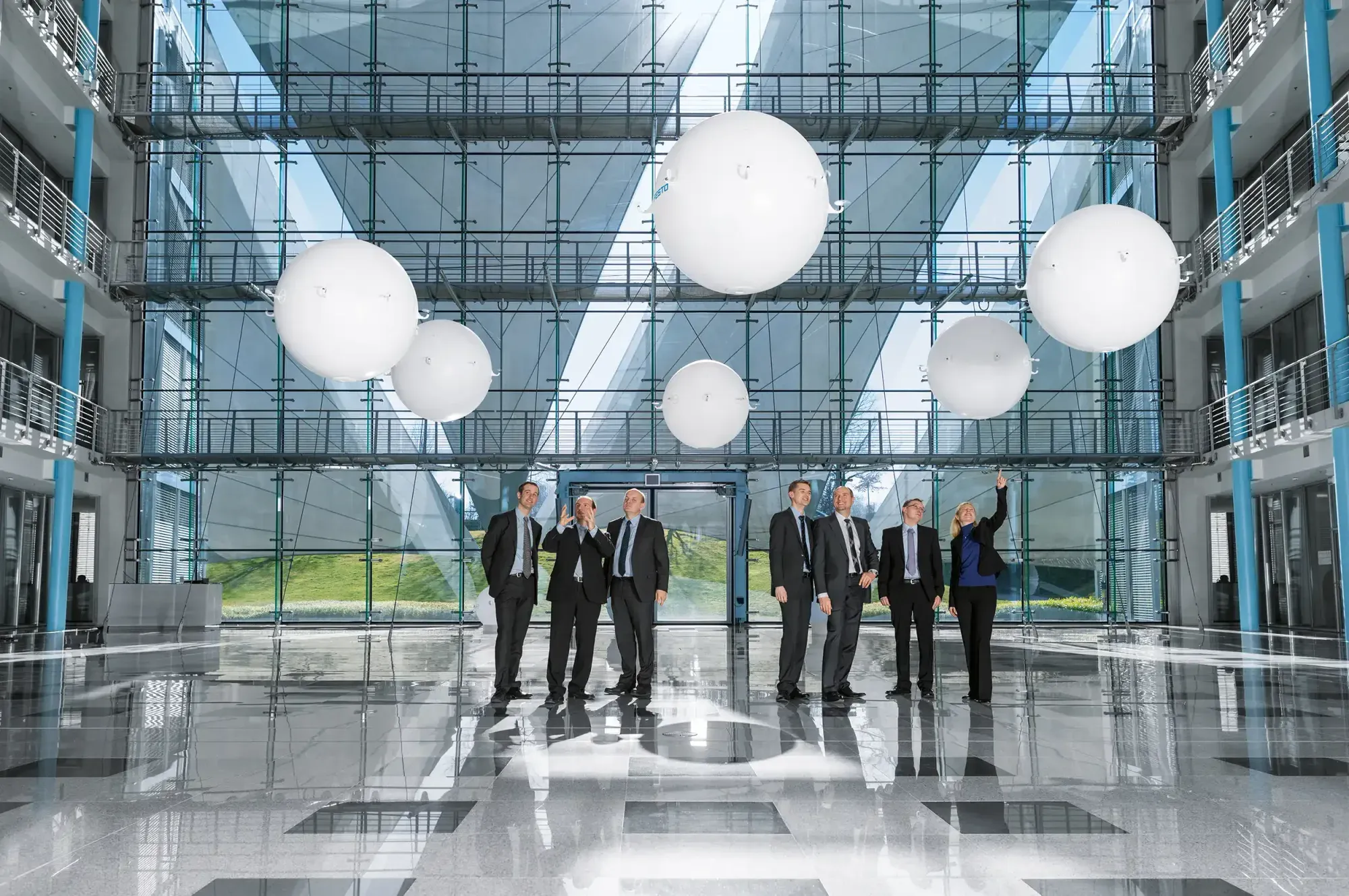 White autonomous spheres floating in formation in a glass atrium