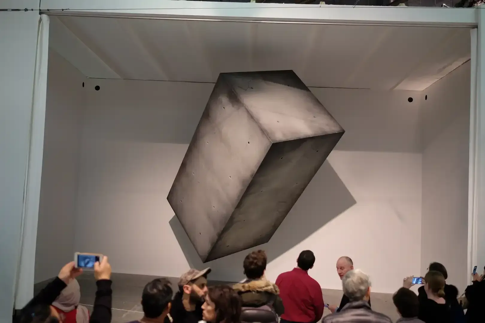 A large concrete block floating and rotating inside a white gallery at the Armory Show, New York