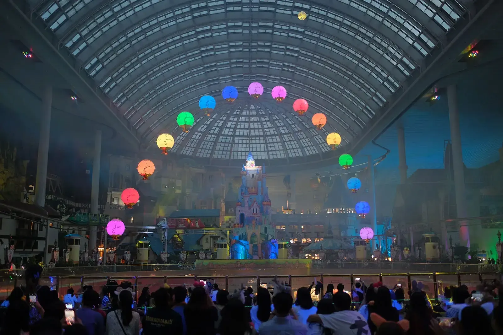 Glowing flying lanterns forming a rainbow arc beneath the dome of Lotte World Adventure, Seoul