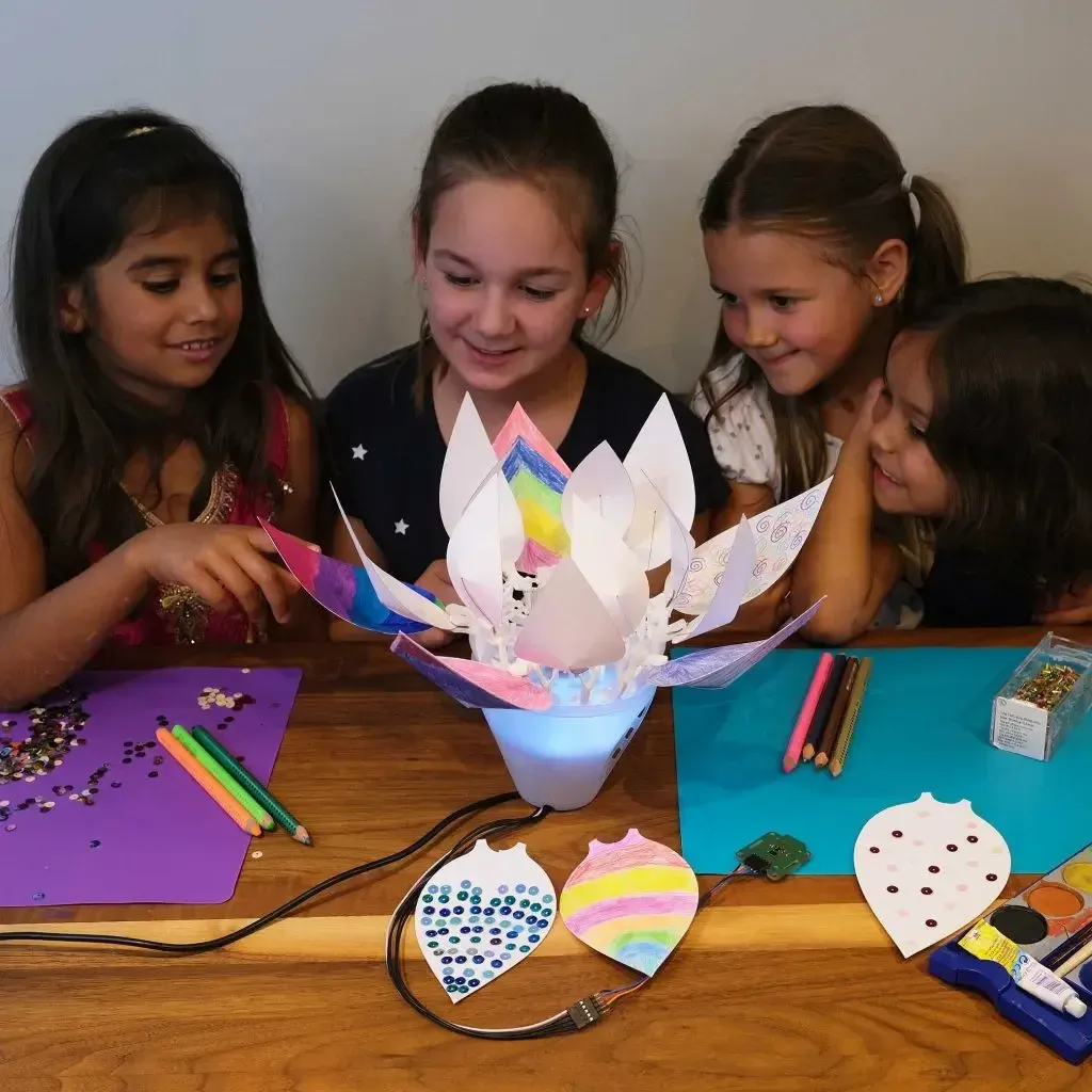 Children building and decorating a robotic bionic flower in a classroom