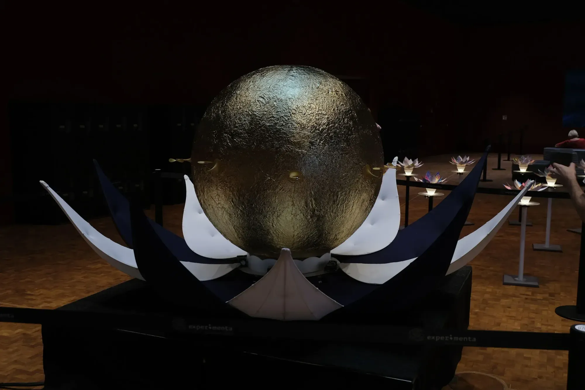 A golden sphere rising out of a giant artificial blossom at the AI Blossom exhibition