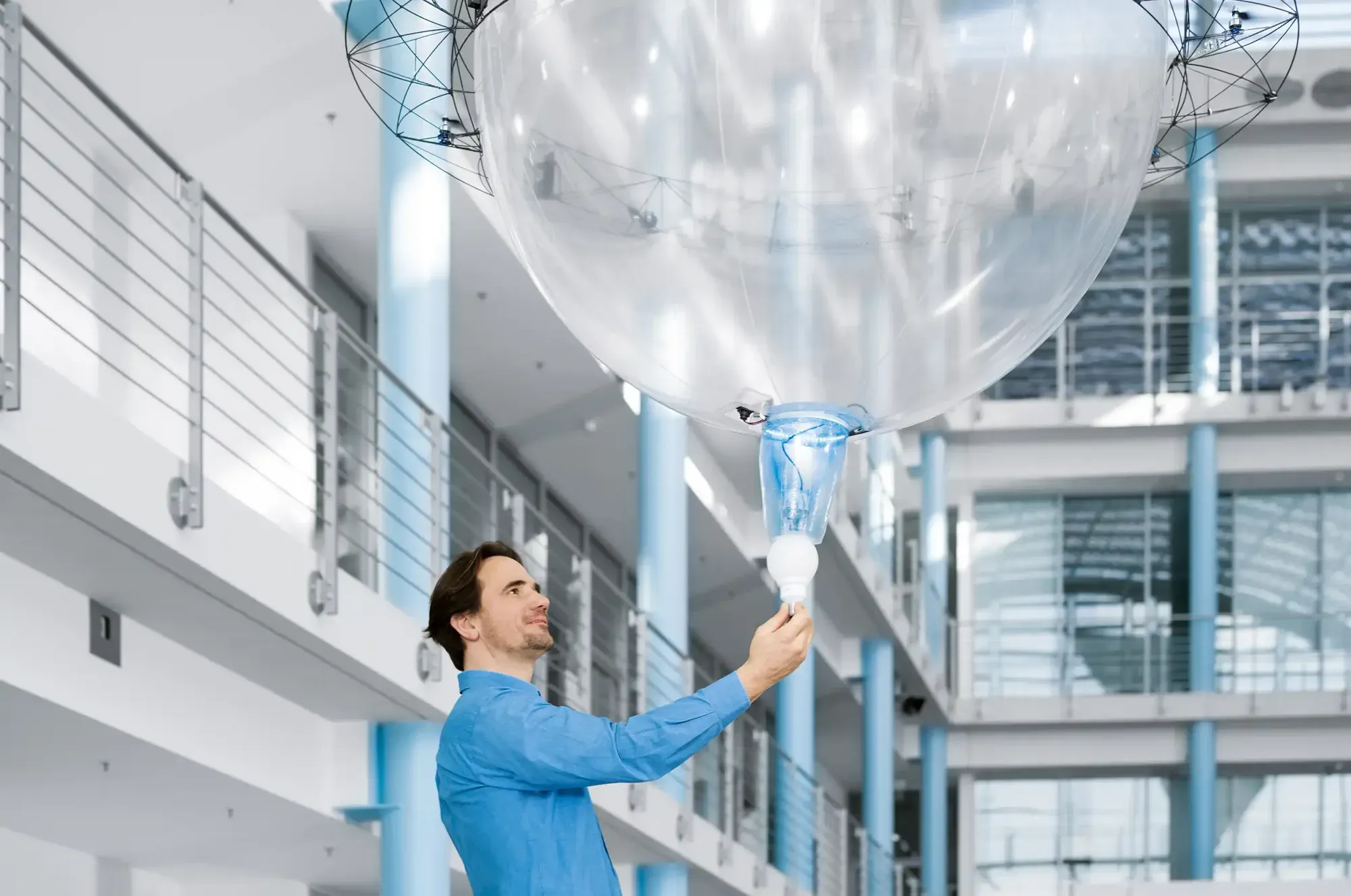 A transparent flying sphere with a gripper handing an object to a person